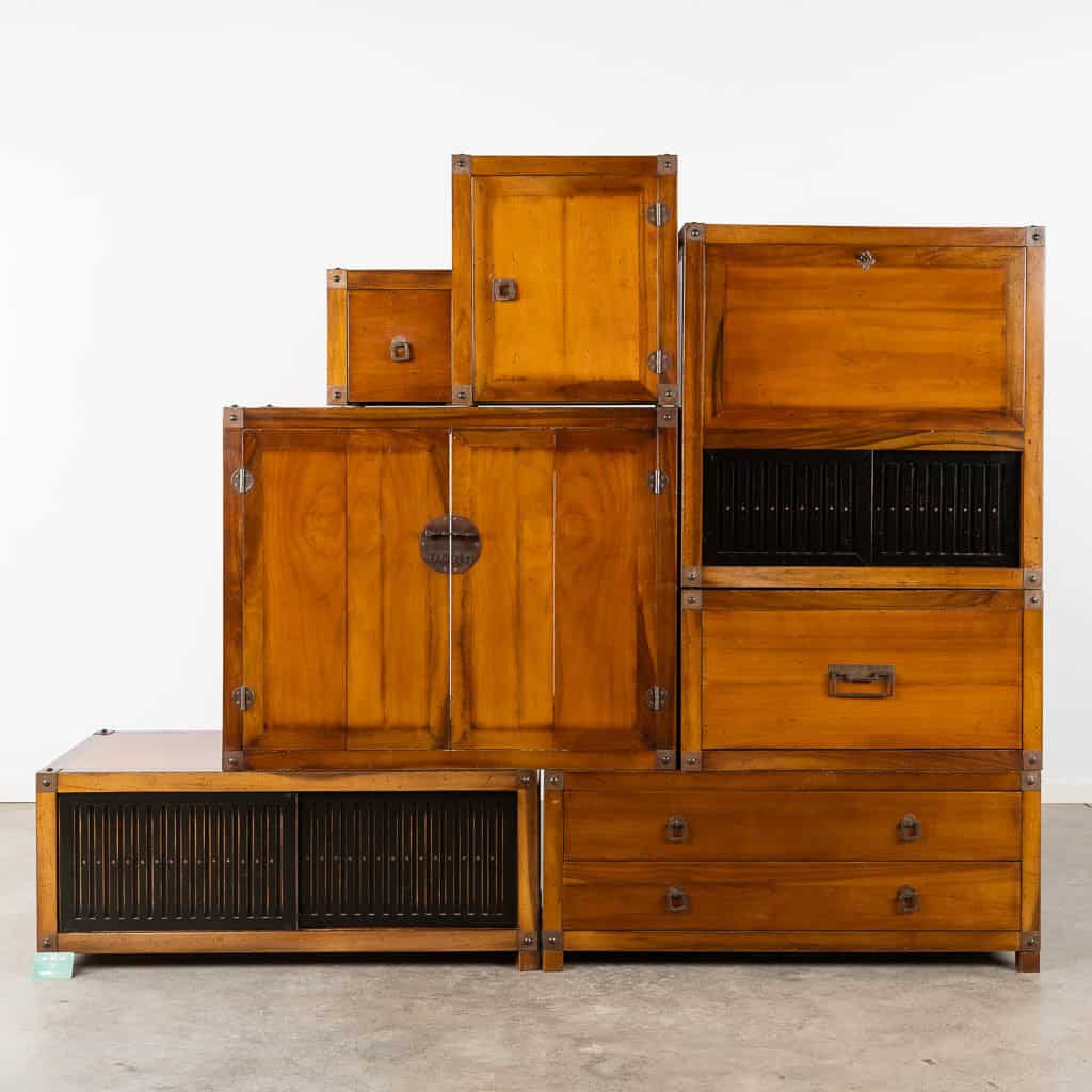 Een set gestapelde vintage houten kasten en lades met metalen accenten, met zowel massieve als lamellendeuren, asymmetrisch gerangschikt tegen een effen witte achtergrond.