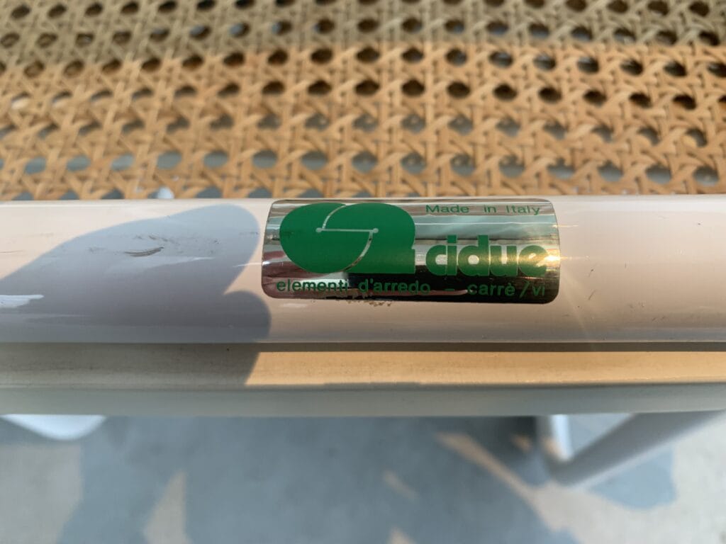 Close-up van een witte metalen staaf met een groen-zilveren sticker met de tekst 