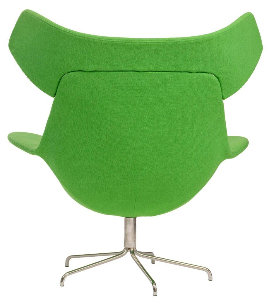 Een moderne groene draaistoel met brede, gebogen armleuningen en een hoge, gevleugelde rugleuning, van achteren gezien. De stoel heeft een metalen onderstel met vier poten.