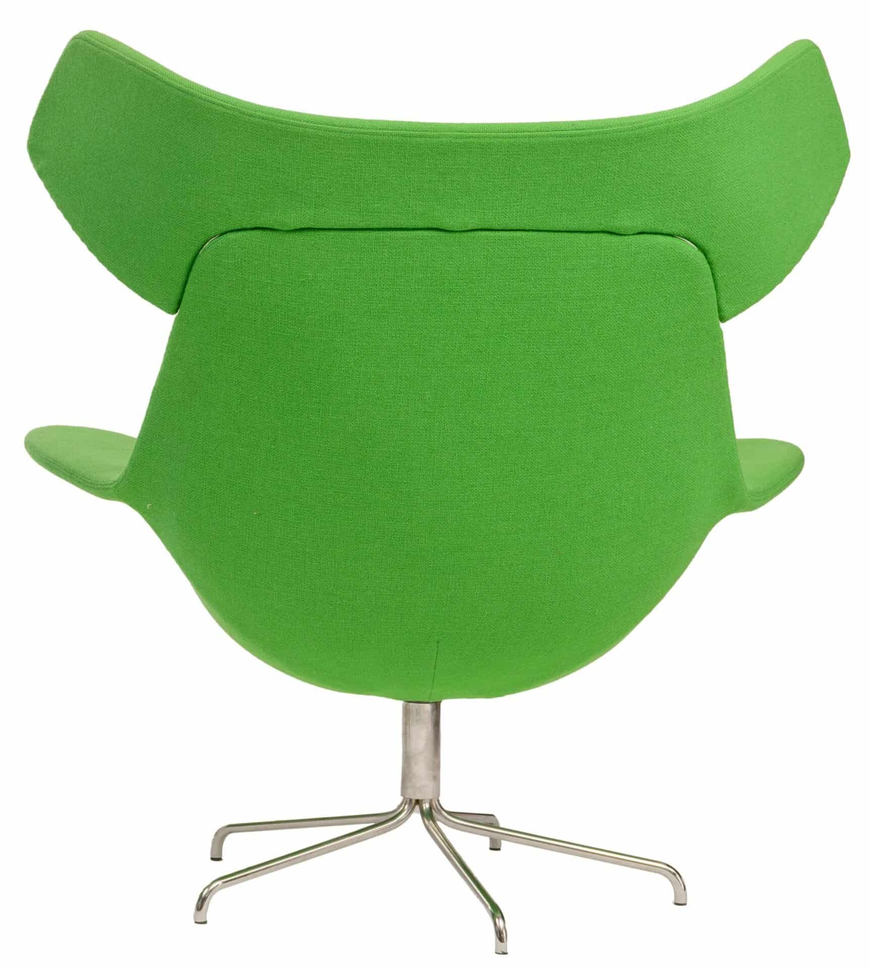 Een moderne groene draaistoel met brede, gebogen armleuningen en een hoge, gevleugelde rugleuning, van achteren gezien. De stoel heeft een metalen onderstel met vier poten.