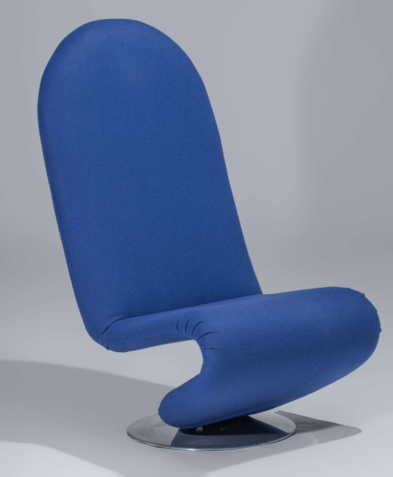 Een moderne, blauw gestoffeerde stoel met een hoge, ronde rugleuning en een gebogen zitting op een rond metalen onderstel, tegen een effen grijze achtergrond.