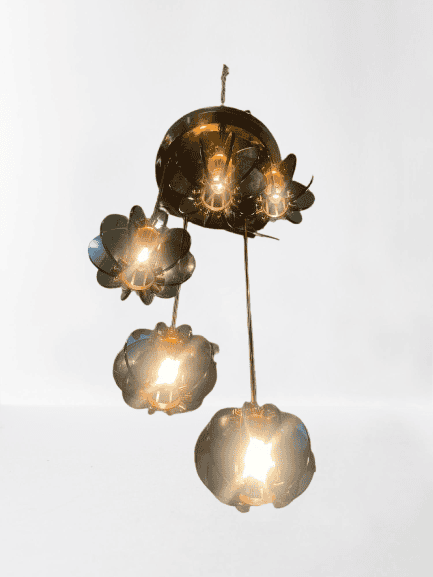 Een antieke kroonluchter van messing met vijf bloemvormige lampenkappen, elk met een gloeiende gloeilamp, hangt aan het plafond tegen een effen witte achtergrond.