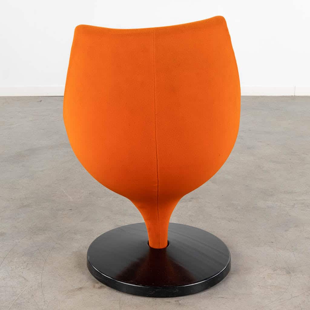 Een moderne stoel met een feloranje, ronde zitting en rugleuning, ondersteund door een zwart rond onderstel. De stoel is van achteren gefotografeerd tegen een effen, lichtgekleurde achtergrond.