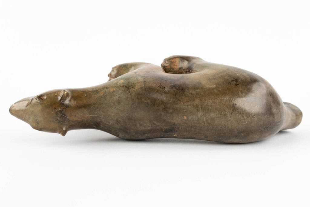 Een glad, bruinachtig bronzen beeld van een liggende beer op zijn zij, met zijn poten ingetrokken en zijn kop naar beneden, tegen een effen witte achtergrond.