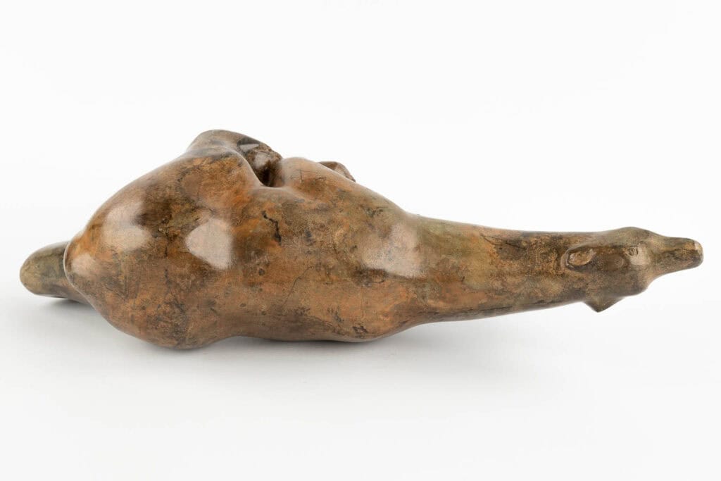 Een glad, abstract bronzen beeld dat lijkt op een liggend, langwerpig dier met minimale gelaatstrekken, tegen een effen witte achtergrond.