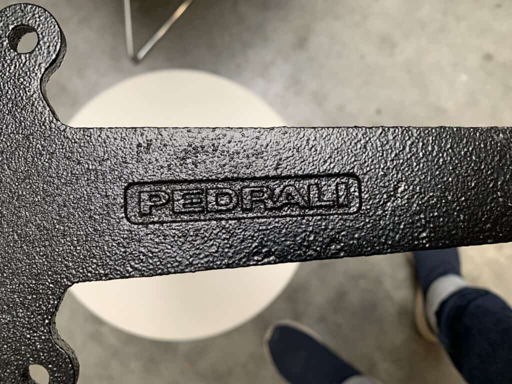 Close-up van een zwart metalen stuk met structuur en het woord 