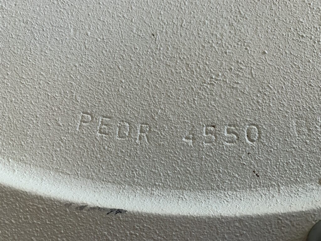 In reliëf gedrukte tekst met de tekst “PEDR 4550” op een gestructureerd, gebroken wit, gebogen oppervlak.